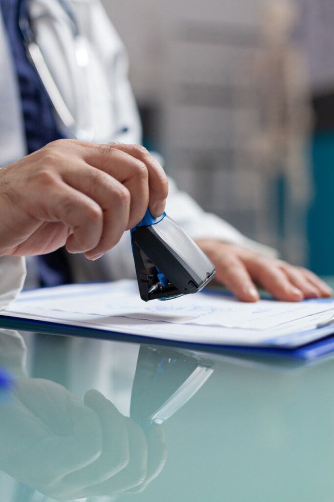 doctor-holding-medical-stamp-put-prescription-paper-health-care-exam-hand-physician-putting-seal-checkup-report-giving-medicine-patient-consultation-close-up